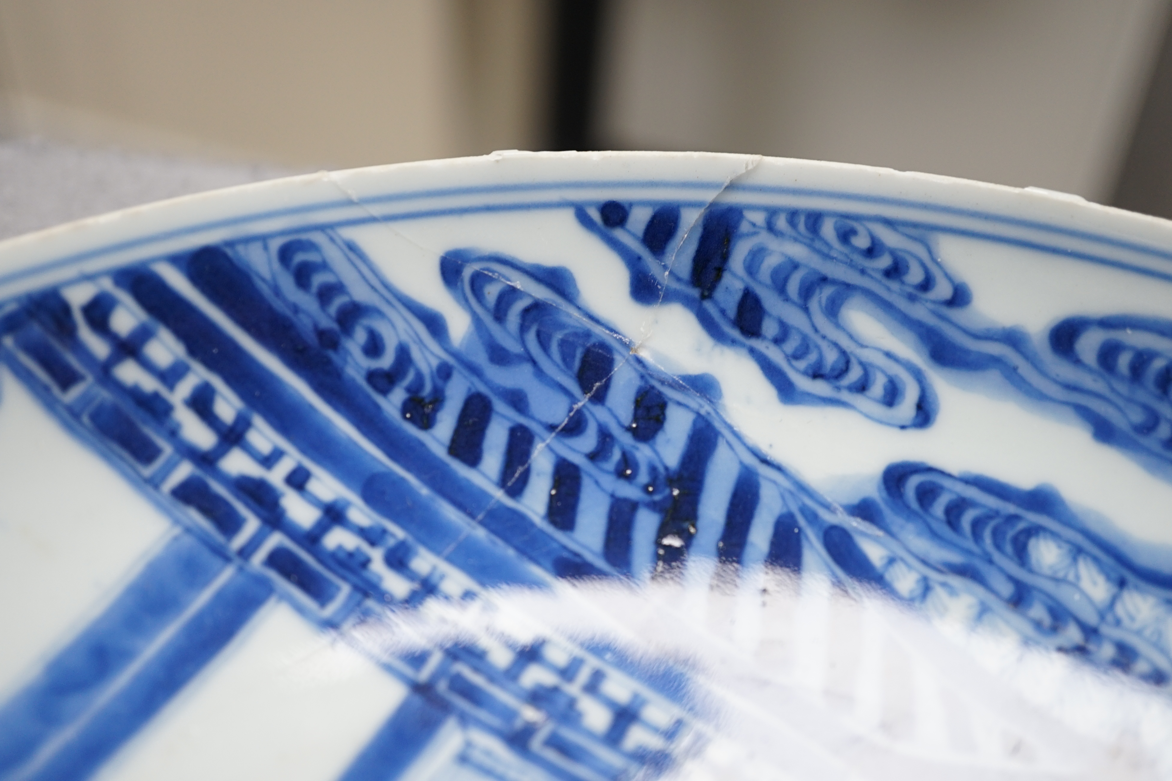 A Chinese blue and white dish, Kangxi period, broken and messily reglued